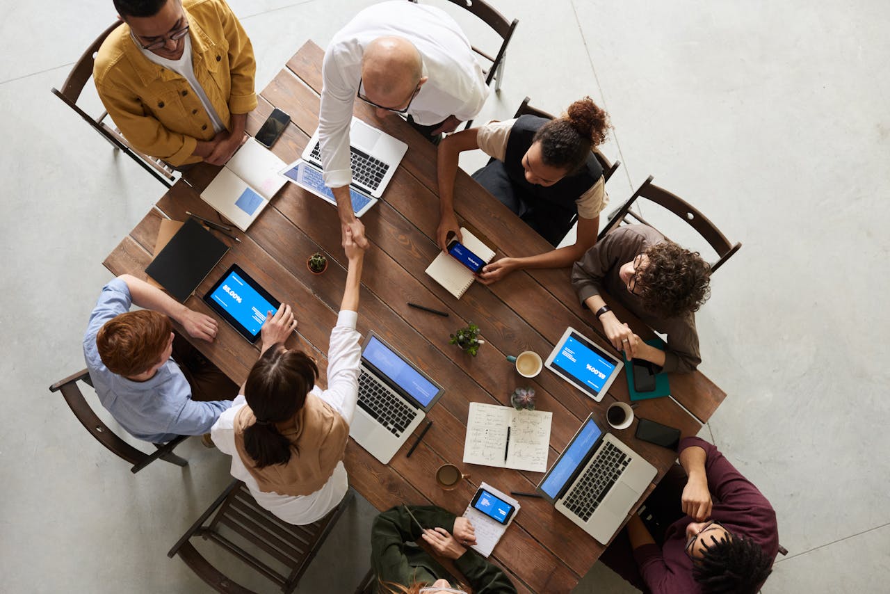 our-services-3 Top view of a diverse team collaborating in an office setting with laptops and tablets, promoting cooperation.