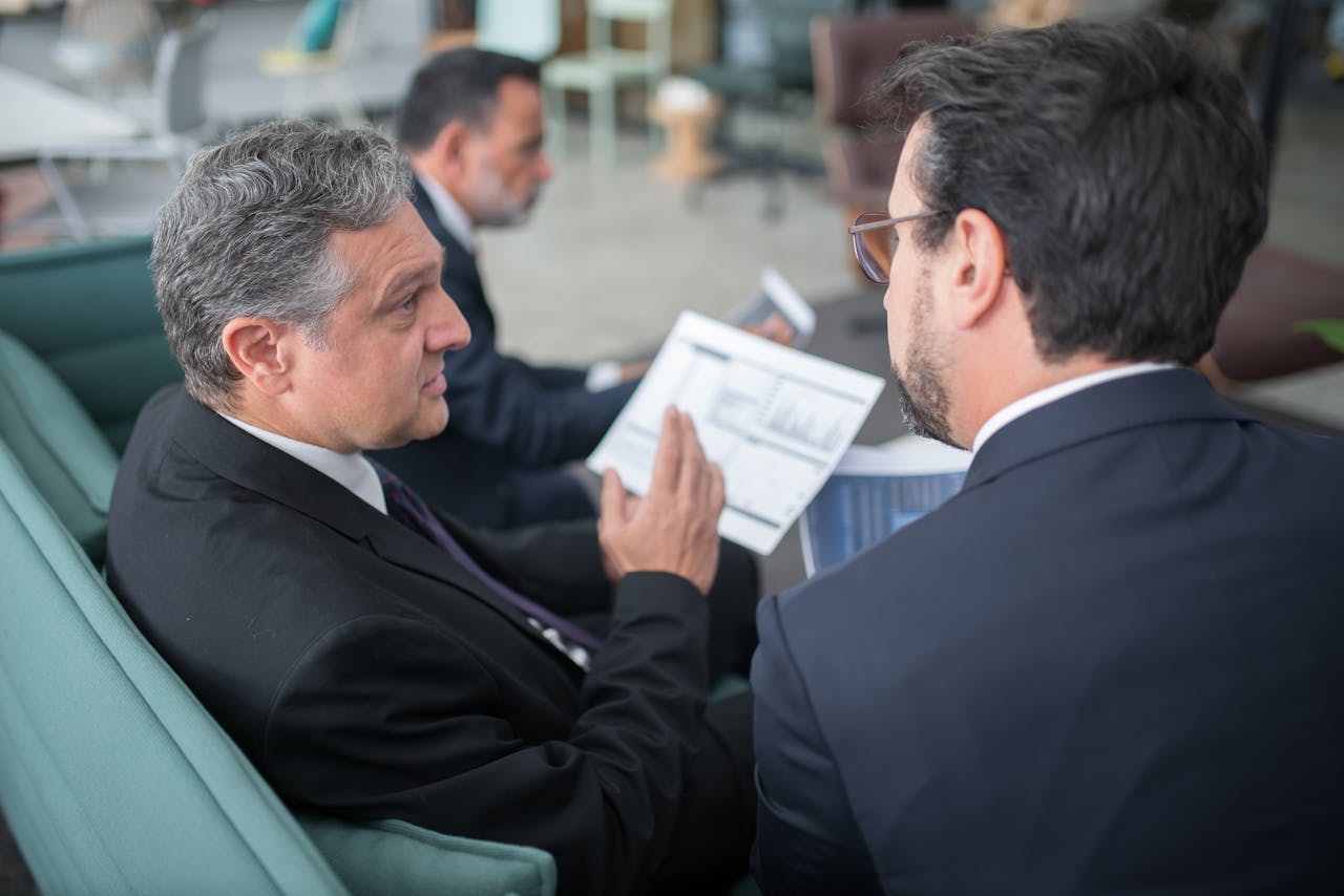 about-01 Two businessmen engaged in a discussion, examining reports in a modern office environment.